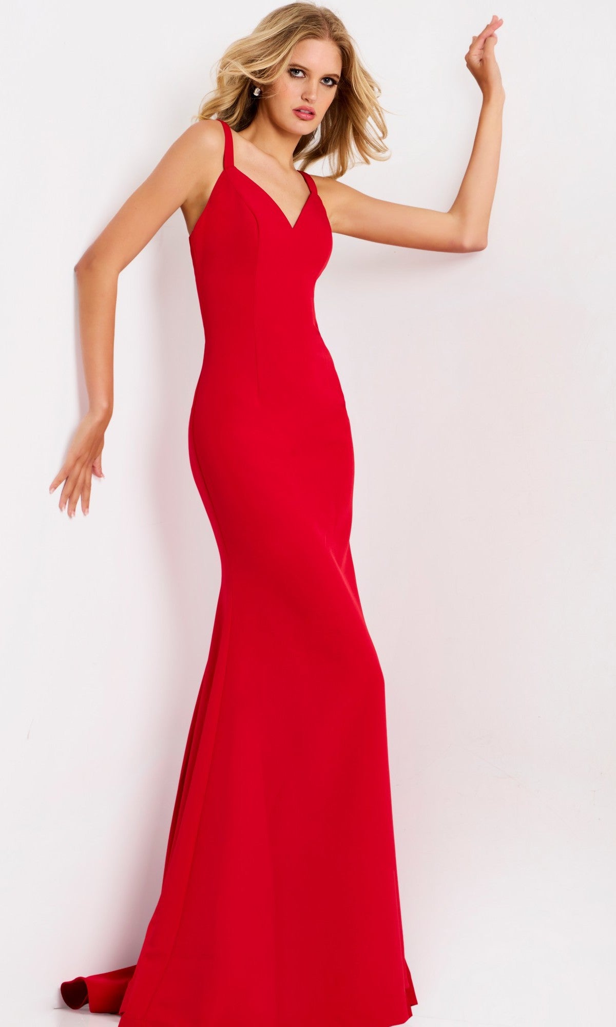 A woman poses against a plain white background wearing the Jovani 49861, a fitted, floor-length red prom dress featuring a strappy open back.